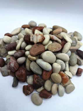 Beyaz arka planda izole edilmiş renkli çakıl taşı. Renkli çakıl taşlarının çeşitli dekoratif ve işlevsel kullanımları vardır, özellikle bahçe düzenlemeleri ve bahçecilikte.