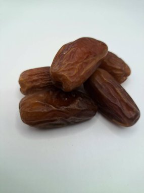 Beyaz arka planda tarihler. Hurma ağacının meyveleri, yumuşak ve tatlı bir ağaçtır. Genellikle ağaçtaki kümelerde bulunurlar ve kahverengiye döndüklerinde ve buruşuklaştıklarında büyük buruşmuş kuru üzümlere benzerler.