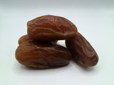 Beyaz arka planda tarihler. Hurma ağacının meyveleri, yumuşak ve tatlı bir ağaçtır. Genellikle ağaçtaki kümelerde bulunurlar ve kahverengiye döndüklerinde ve buruşuklaştıklarında büyük buruşmuş kuru üzümlere benzerler.