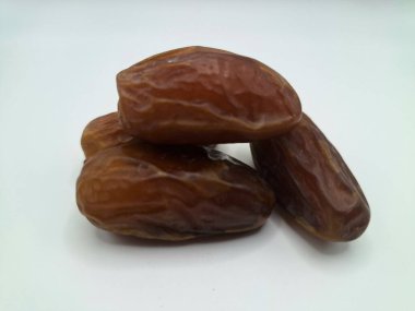 Beyaz arka planda tarihler. Hurma ağacının meyveleri, yumuşak ve tatlı bir ağaçtır. Genellikle ağaçtaki kümelerde bulunurlar ve kahverengiye döndüklerinde ve buruşuklaştıklarında büyük buruşmuş kuru üzümlere benzerler.