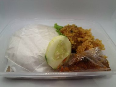 Dilimlenmiş salatalık ve biber sosuyla servis edilen kızarmış tavuk ve pilav plastik bir kabın içinde.