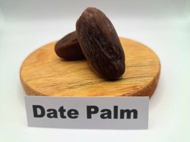 Yuvarlak tahta üzerinde tarihler. Hurma ağacının meyveleri, yumuşak ve tatlı bir ağaçtır. Genellikle ağaçtaki kümelerde bulunurlar ve kahverengiye döndüklerinde ve buruşuklaştıklarında büyük buruşmuş kuru üzümlere benzerler.