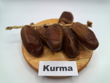 Yuvarlak tahta üzerinde tarihler. Hurma ağacının meyveleri, yumuşak ve tatlı bir ağaçtır. Genellikle ağaçtaki kümelerde bulunurlar ve kahverengiye döndüklerinde ve buruşuklaştıklarında büyük buruşmuş kuru üzümlere benzerler.