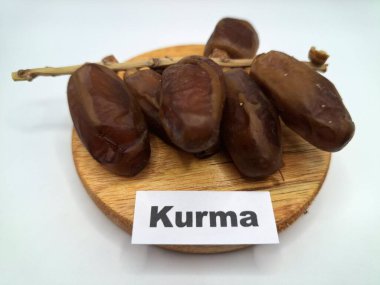 Yuvarlak tahta üzerinde tarihler. Hurma ağacının meyveleri, yumuşak ve tatlı bir ağaçtır. Genellikle ağaçtaki kümelerde bulunurlar ve kahverengiye döndüklerinde ve buruşuklaştıklarında büyük buruşmuş kuru üzümlere benzerler.