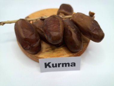 Yuvarlak tahta üzerinde tarihler. Hurma ağacının meyveleri, yumuşak ve tatlı bir ağaçtır. Genellikle ağaçtaki kümelerde bulunurlar ve kahverengiye döndüklerinde ve buruşuklaştıklarında büyük buruşmuş kuru üzümlere benzerler.