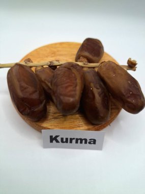 Yuvarlak tahta üzerinde tarihler. Hurma ağacının meyveleri, yumuşak ve tatlı bir ağaçtır. Genellikle ağaçtaki kümelerde bulunurlar ve kahverengiye döndüklerinde ve buruşuklaştıklarında büyük buruşmuş kuru üzümlere benzerler.