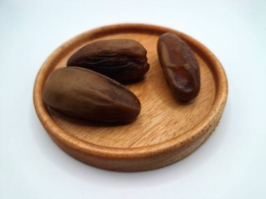 Küçük ahşap bir tabakta meyve. Hurma ağacından sarkan tatlı meyveler. Tek bir tohumla çevrili, tatlı, etli, kahverengi, koyu kahverengi ya da sarı renkli bir meyvedir.