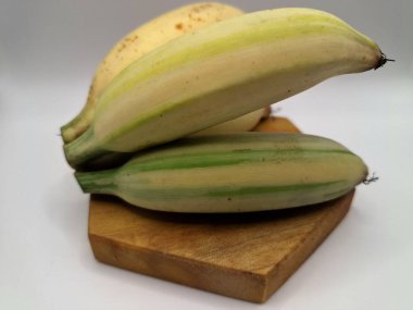 Florida 'nın çeşitli muz meyveleri ahşap servis tahtasının üzerinde. Bu, çarpıcı çeşitlilikteki yaprakları ve meyveleriyle eşsiz bir muz çeşididir. Güzel yapraklarından dolayı süs için yetiştirilirken, aynı zamanda yenilebilir de.