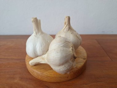 Tahta servis tahtasındaki sarımsak soğanları. Sarımsak, Allium ailesinden gelen soğanlı bir bitkidir. Güçlü, keskin kokusu ve tadı ile karakterize edilir. Sarımsak yaygın olarak mutfak aroması olarak kullanılır ve aynı zamanda tıbbi özelliklere sahiptir.