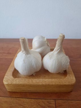 Tahta servis tahtasındaki sarımsak soğanları. Sarımsak, Allium ailesinden gelen soğanlı bir bitkidir. Güçlü, keskin kokusu ve tadı ile karakterize edilir. Sarımsak yaygın olarak mutfak aroması olarak kullanılır ve aynı zamanda tıbbi özelliklere sahiptir.