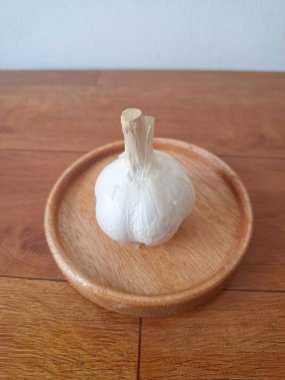 Tahta servis tahtasındaki sarımsak soğanları. Sarımsak, Allium ailesinden gelen soğanlı bir bitkidir. Güçlü, keskin kokusu ve tadı ile karakterize edilir. Sarımsak yaygın olarak mutfak aroması olarak kullanılır ve aynı zamanda tıbbi özelliklere sahiptir.