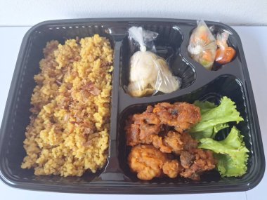 Endonezya 'dan geleneksel beslenme çantası. Bu beslenme çantası genellikle sarı pilav içerir ve kızarmış tavuk, kraker, marul ve Endonezya biber sosuyla servis edilir.