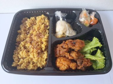 Endonezya 'dan geleneksel beslenme çantası. Bu beslenme çantası genellikle sarı pilav içerir ve kızarmış tavuk, kraker, marul ve Endonezya biber sosuyla servis edilir.
