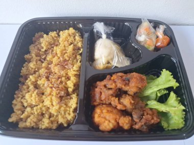 Endonezya 'dan geleneksel beslenme çantası. Bu beslenme çantası genellikle sarı pilav içerir ve kızarmış tavuk, kraker, marul ve Endonezya biber sosuyla servis edilir.