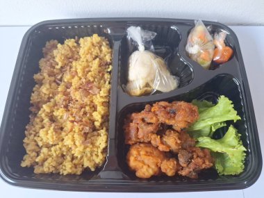 Endonezya 'dan geleneksel beslenme çantası. Bu beslenme çantası genellikle sarı pilav içerir ve kızarmış tavuk, kraker, marul ve Endonezya biber sosuyla servis edilir.