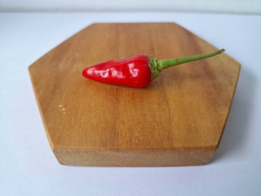 Ahşap servis tahtasında kırmızı kırmızıbiber. Kırmızı biber, acı bir tadı olan ve genellikle yemek ve tıpta kullanılan bir kırmızı biber türüdür. Bu biber ince şekli, parlak kırmızı rengi ve yüksek baharat seviyesi ile bilinir.