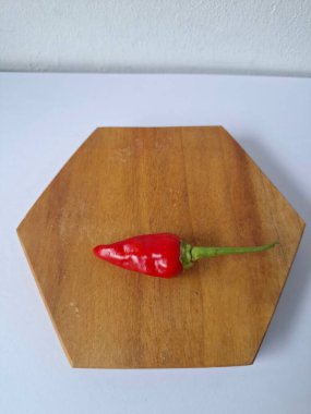 Ahşap servis tahtasında kırmızı kırmızıbiber. Kırmızı biber, acı bir tadı olan ve genellikle yemek ve tıpta kullanılan bir kırmızı biber türüdür. Bu biber ince şekli, parlak kırmızı rengi ve yüksek baharat seviyesi ile bilinir.