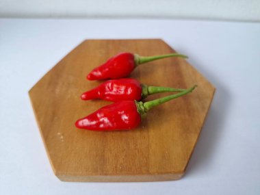 Ahşap servis tahtasında kırmızı kırmızıbiber. Kırmızı biber, acı bir tadı olan ve genellikle yemek ve tıpta kullanılan bir kırmızı biber türüdür. Bu biber ince şekli, parlak kırmızı rengi ve yüksek baharat seviyesi ile bilinir.