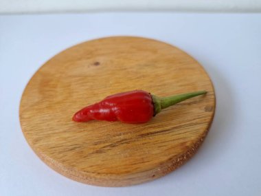 Yuvarlak tahta üzerinde kırmızı biber. Acı bir tadı olan ve sıklıkla yemek ve tıpta kullanılan bir biber türüdür. Bu kırmızı biber ince şekli, parlak kırmızı rengi ve yüksek seviye...