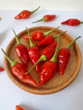 Ahşap servis tabağında kırmızı biber. Acı bir tadı olan ve sıklıkla yemek ve tıpta kullanılan bir biber türüdür. Bu kırmızı biber ince şekli, parlak kırmızı rengi ve yüksek seviye...
