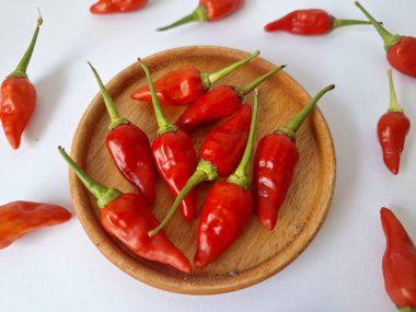Ahşap servis tabağında kırmızı biber. Acı bir tadı olan ve sıklıkla yemek ve tıpta kullanılan bir biber türüdür. Bu kırmızı biber ince şekli, parlak kırmızı rengi ve yüksek seviye...