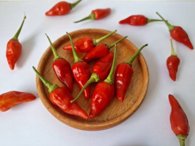 Ahşap servis tabağında kırmızı biber. Acı bir tadı olan ve sıklıkla yemek ve tıpta kullanılan bir biber türüdür. Bu kırmızı biber ince şekli, parlak kırmızı rengi ve yüksek seviye...