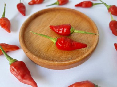 Ahşap servis tabağında kırmızı biber. Acı bir tadı olan ve sıklıkla yemek ve tıpta kullanılan bir biber türüdür. Bu kırmızı biber ince şekli, parlak kırmızı rengi ve yüksek seviye...