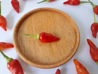 Ahşap servis tabağında kırmızı biber. Acı bir tadı olan ve sıklıkla yemek ve tıpta kullanılan bir biber türüdür. Bu kırmızı biber ince şekli, parlak kırmızı rengi ve yüksek seviye...