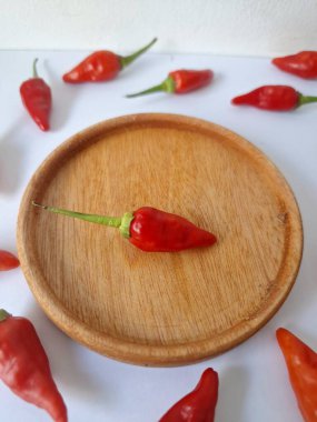 Ahşap servis tabağında kırmızı biber. Acı bir tadı olan ve sıklıkla yemek ve tıpta kullanılan bir biber türüdür. Bu kırmızı biber ince şekli, parlak kırmızı rengi ve yüksek seviye...