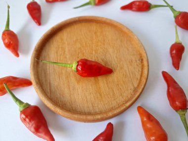 Ahşap servis tabağında kırmızı biber. Acı bir tadı olan ve sıklıkla yemek ve tıpta kullanılan bir biber türüdür. Bu kırmızı biber ince şekli, parlak kırmızı rengi ve yüksek seviye...
