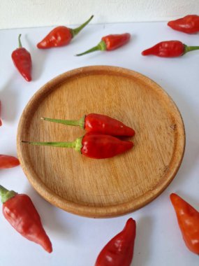 Ahşap servis tabağında kırmızı biber. Acı bir tadı olan ve sıklıkla yemek ve tıpta kullanılan bir biber türüdür. Bu kırmızı biber ince şekli, parlak kırmızı rengi ve yüksek seviye...