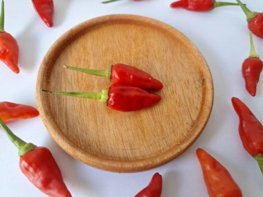 Ahşap servis tabağında kırmızı biber. Acı bir tadı olan ve sıklıkla yemek ve tıpta kullanılan bir biber türüdür. Bu kırmızı biber ince şekli, parlak kırmızı rengi ve yüksek seviye...