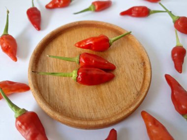 Ahşap servis tabağında kırmızı biber. Acı bir tadı olan ve sıklıkla yemek ve tıpta kullanılan bir biber türüdür. Bu kırmızı biber ince şekli, parlak kırmızı rengi ve yüksek seviye...