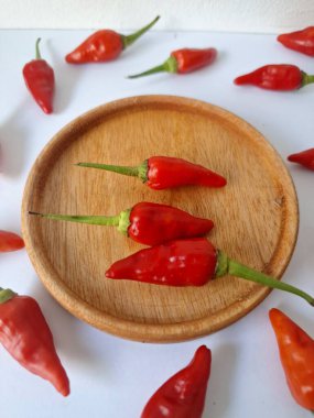 Ahşap servis tabağında kırmızı biber. Acı bir tadı olan ve sıklıkla yemek ve tıpta kullanılan bir biber türüdür. Bu kırmızı biber ince şekli, parlak kırmızı rengi ve yüksek seviye...