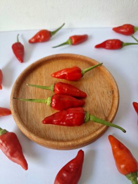 Ahşap servis tabağında kırmızı biber. Acı bir tadı olan ve sıklıkla yemek ve tıpta kullanılan bir biber türüdür. Bu kırmızı biber ince şekli, parlak kırmızı rengi ve yüksek seviye...