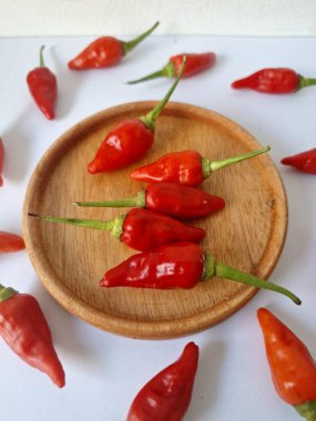 Ahşap servis tabağında kırmızı biber. Acı bir tadı olan ve sıklıkla yemek ve tıpta kullanılan bir biber türüdür. Bu kırmızı biber ince şekli, parlak kırmızı rengi ve yüksek seviye...