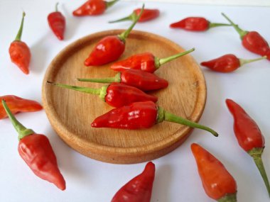 Ahşap servis tabağında kırmızı biber. Acı bir tadı olan ve sıklıkla yemek ve tıpta kullanılan bir biber türüdür. Bu kırmızı biber ince şekli, parlak kırmızı rengi ve yüksek seviye...