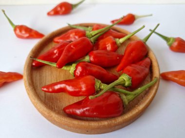 Ahşap servis tabağında kırmızı biber. Acı bir tadı olan ve sıklıkla yemek ve tıpta kullanılan bir biber türüdür. Bu kırmızı biber ince şekli, parlak kırmızı rengi ve yüksek seviye...