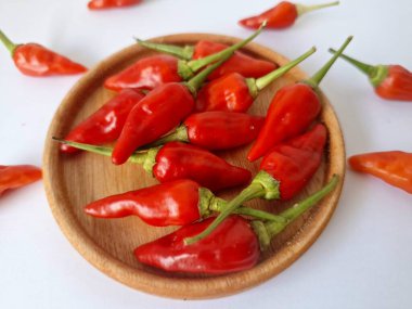 Ahşap servis tabağında kırmızı biber. Acı bir tadı olan ve sıklıkla yemek ve tıpta kullanılan bir biber türüdür. Bu kırmızı biber ince şekli, parlak kırmızı rengi ve yüksek seviye...