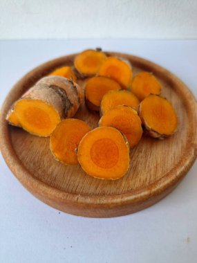 Küçük ahşap tabakta zerdeçal boruları. Zerdeçal öncelikle Asya mutfağında ve potansiyel sağlık yararları için yemek pişirmede bir baharat olarak kullanılır. Zemin baharatı ve taze kökler gibi çeşitli şekillerde de kullanılır.