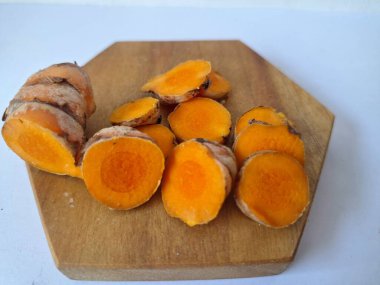 Servis tahtasında taze zerdeçal yumrusu dilimleri. Bu baharat Asya mutfağında yaygın olarak kullanılır, özellikle köri gibi yemeklerde tat ve renk için. Zerdeçal ayrıca aktif bileşik curkiminle birlikte tıbbi özelliklere de sahiptir.