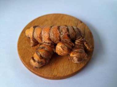 Yuvarlak ahşap bir tahtanın üzerindeki zerdeçal boruları. Zerdeçal öncelikle Asya mutfağında ve potansiyel sağlık yararları için yemek pişirmede bir baharat olarak kullanılır. Zemin baharatı ve taze kökler gibi çeşitli şekillerde de kullanılır.