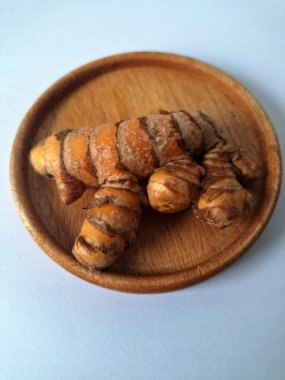 Küçük ahşap bir tabakta zerdeçal boruları. Zerdeçal öncelikle Asya mutfağında ve potansiyel sağlık yararları için yemek pişirmede bir baharat olarak kullanılır. Curcuma longa bitkisinin zencefille ilgili bir ritmi.