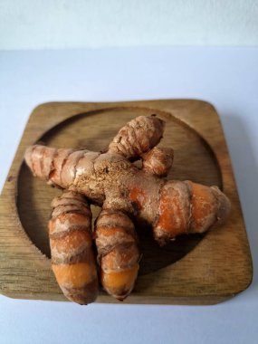 Tahta servis tahtasındaki zerdeçal ritmi. Zerdeçal öncelikle Asya mutfağında ve potansiyel sağlık yararları için yemek pişirmede bir baharat olarak kullanılır. Curcuma longa bitkisinin zencefille ilgili bir ritmi.