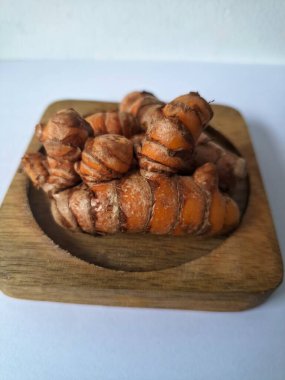 Tahta servis tahtasındaki zerdeçal ritmi. Zerdeçal öncelikle Asya mutfağında ve potansiyel sağlık yararları için yemek pişirmede bir baharat olarak kullanılır. Curcuma longa bitkisinin zencefille ilgili bir ritmi.