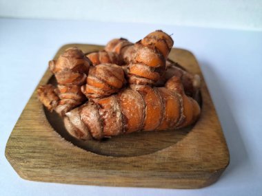 Tahta servis tahtasındaki zerdeçal ritmi. Zerdeçal öncelikle Asya mutfağında ve potansiyel sağlık yararları için yemek pişirmede bir baharat olarak kullanılır. Curcuma longa bitkisinin zencefille ilgili bir ritmi.