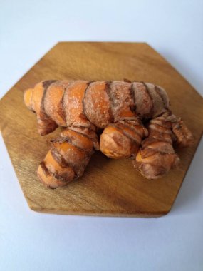 Tahta servis tahtasındaki zerdeçal ritmi. Zerdeçal öncelikle Asya mutfağında ve potansiyel sağlık yararları için yemek pişirmede bir baharat olarak kullanılır. Curcuma longa bitkisinin zencefille ilgili bir ritmi.