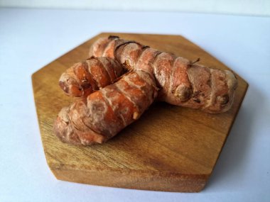 Tahta servis tahtasındaki zerdeçal ritmi. Zerdeçal öncelikle Asya mutfağında ve potansiyel sağlık yararları için yemek pişirmede bir baharat olarak kullanılır. Curcuma longa bitkisinin zencefille ilgili bir ritmi.