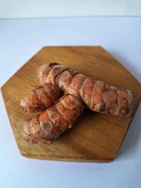 Tahta servis tahtasındaki zerdeçal ritmi. Zerdeçal öncelikle Asya mutfağında ve potansiyel sağlık yararları için yemek pişirmede bir baharat olarak kullanılır. Curcuma longa bitkisinin zencefille ilgili bir ritmi.