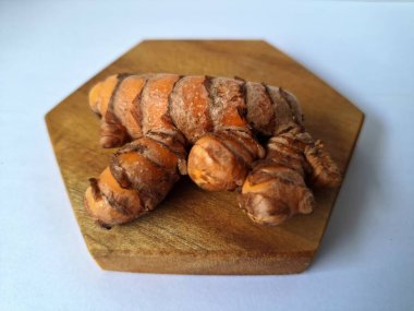 Tahta servis tahtasındaki zerdeçal ritmi. Zerdeçal öncelikle Asya mutfağında ve potansiyel sağlık yararları için yemek pişirmede bir baharat olarak kullanılır. Curcuma longa bitkisinin zencefille ilgili bir ritmi.